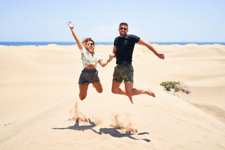 Young beautiful couple smiling happy and confident. Jumping with smile on face at the beach